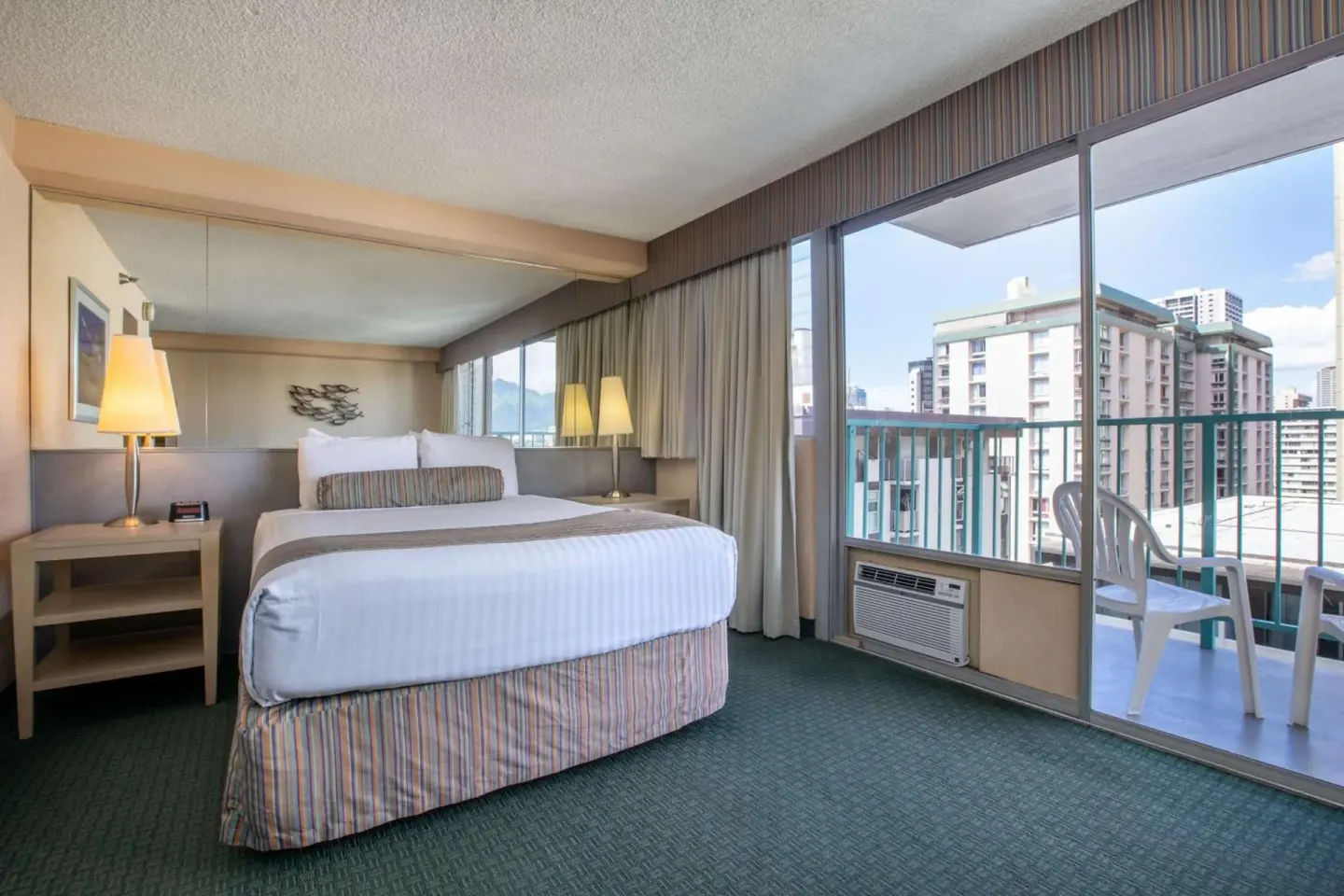 Guest room with king bed, mirrored wall, and balcony doors at Aqua Aloha Surf Waikiki.