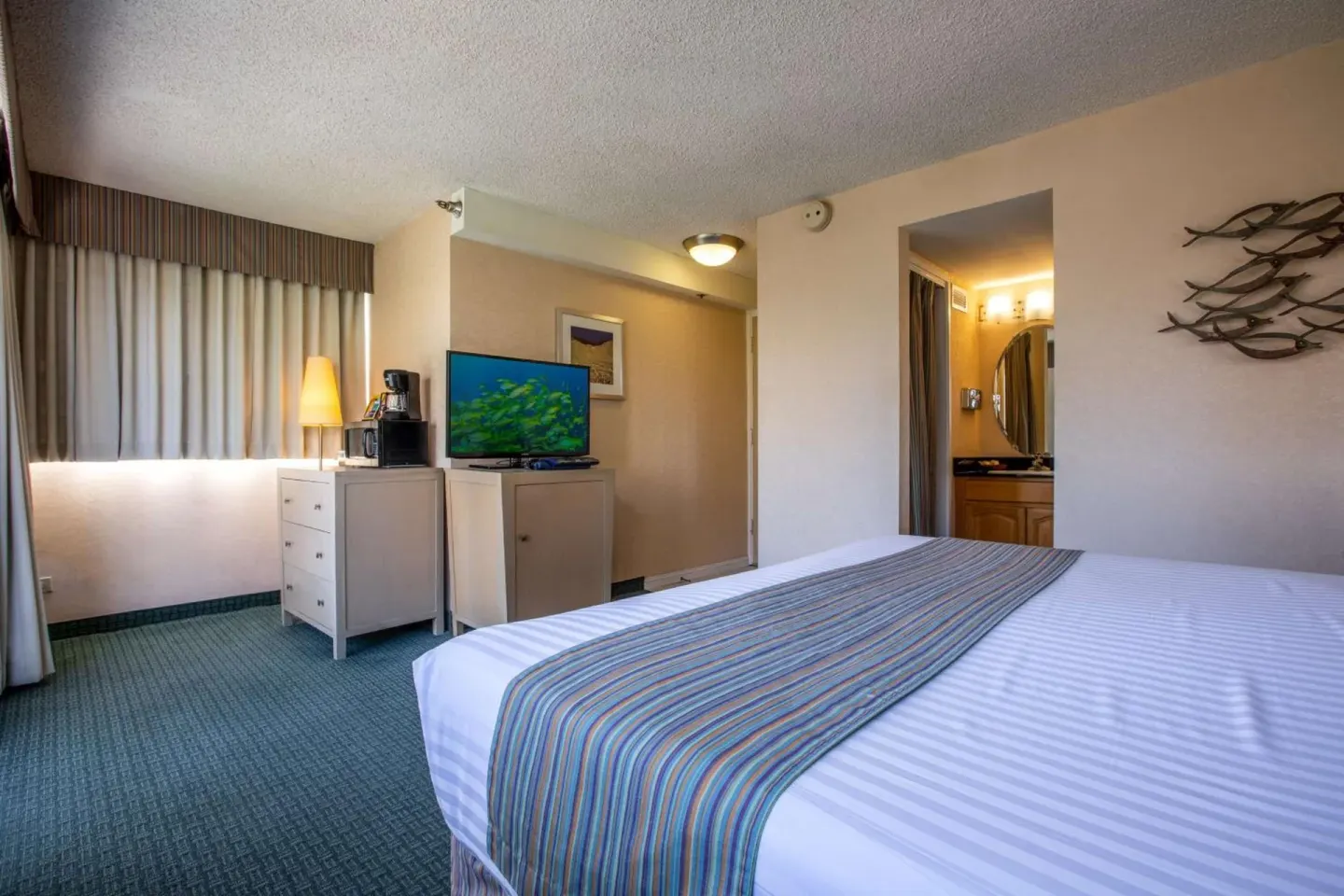 Guest room with king bed, TV, and vanity area at Aqua Aloha Surf Waikiki.