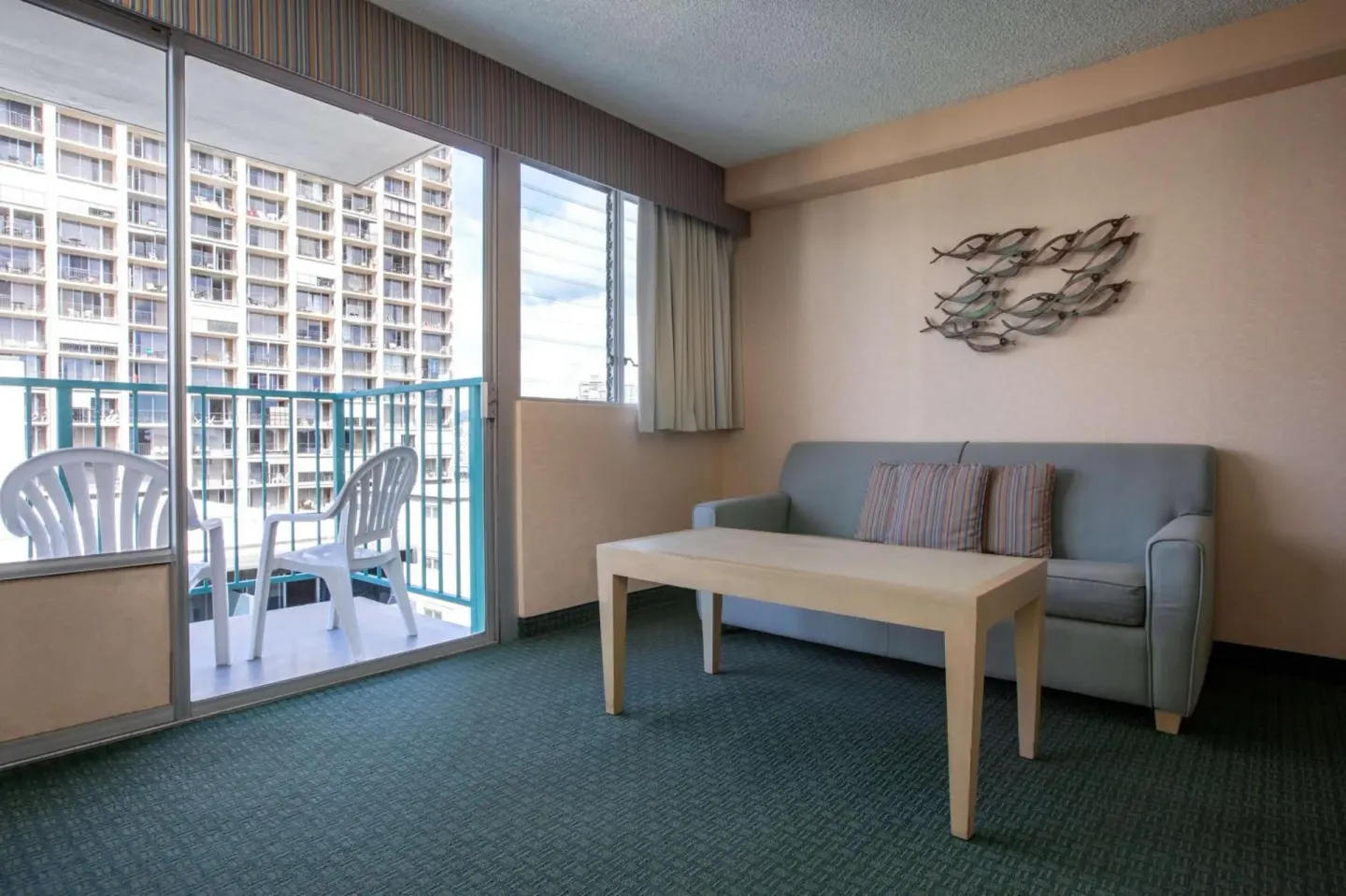 Guest room sitting area with sofa and balcony at Aqua Aloha Surf Waikiki.