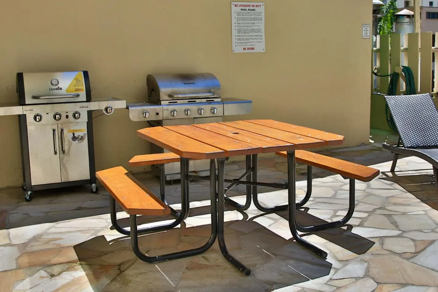 Outdoor barbecue area with grills, picnic table, and lounge chair at Aqua Aloha Surf Waikiki.