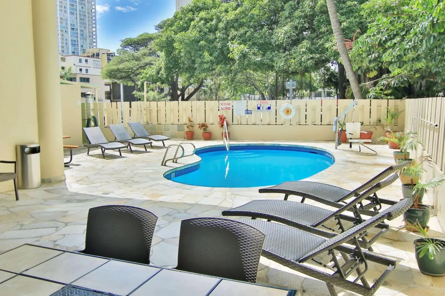Outdoor pool deck with lounge chairs and potted plants at Aqua Aloha Surf Waikiki.