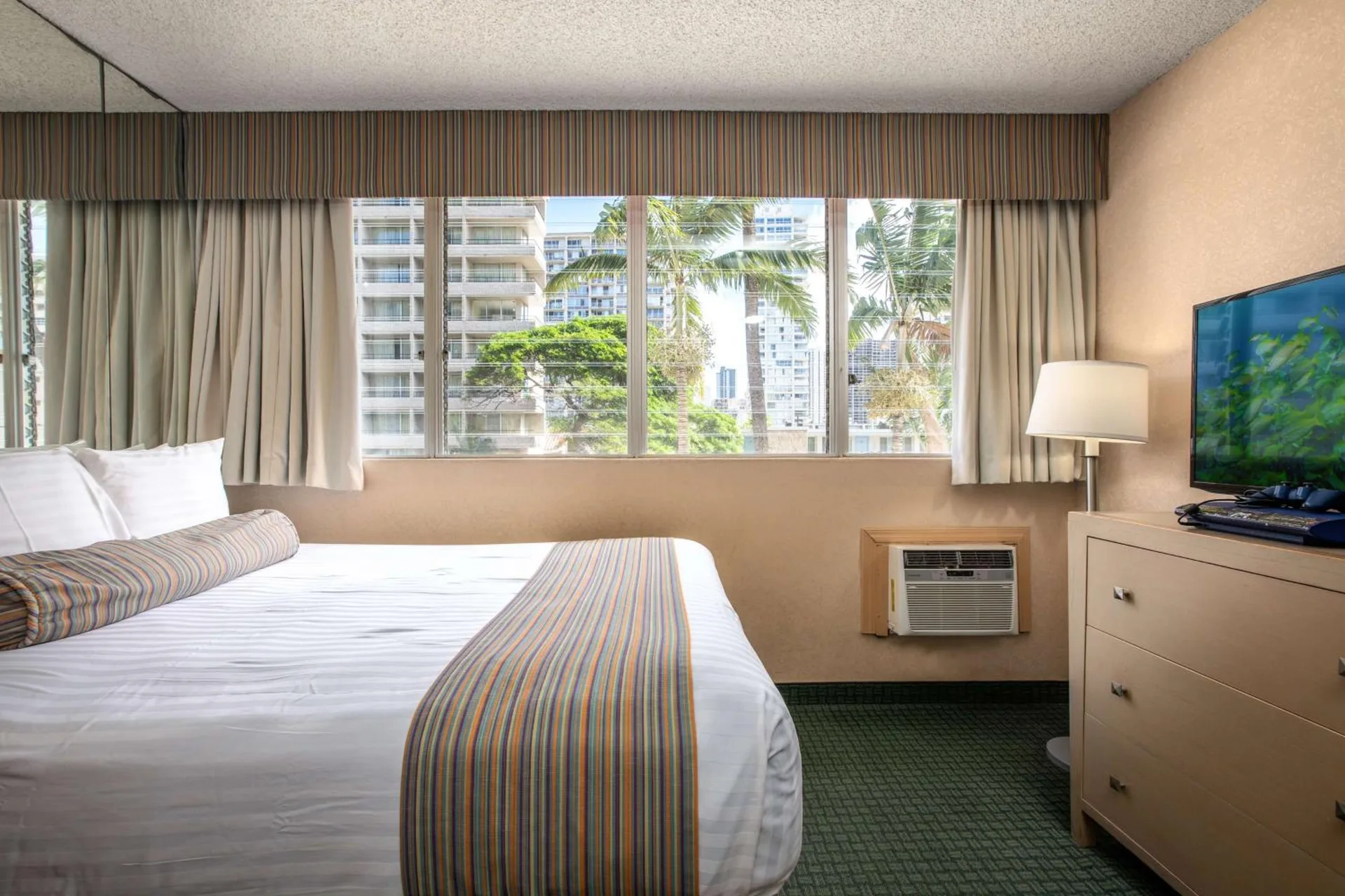 Moderate room with king bed, window, dresser, TV, and lamp at Aqua Aloha Surf Waikiki.