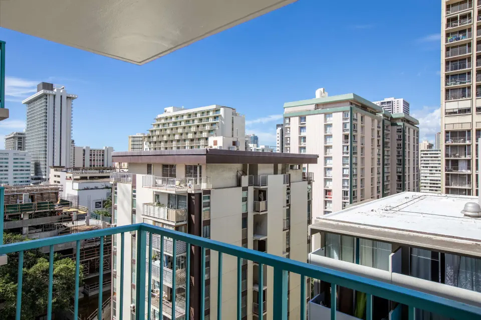 Deluxe Room balcony city view at Aqua Aloha Surf Waikiki with railings and nearby high-rise buildings.