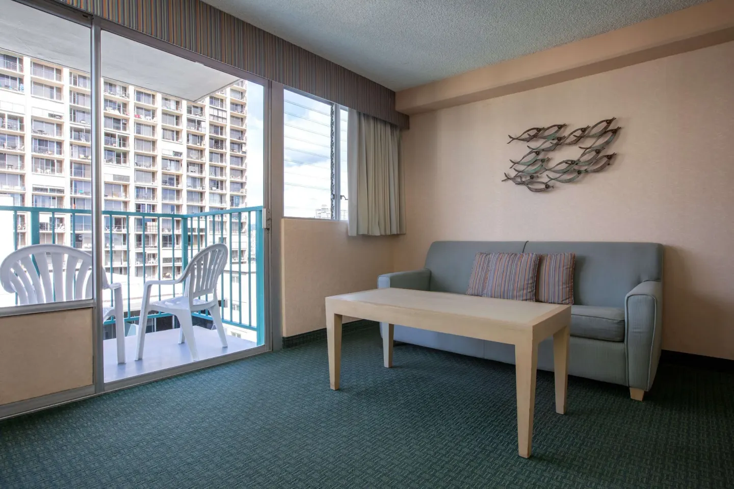 Deluxe Room sofa area and balcony seating at Aqua Aloha Surf Waikiki.
