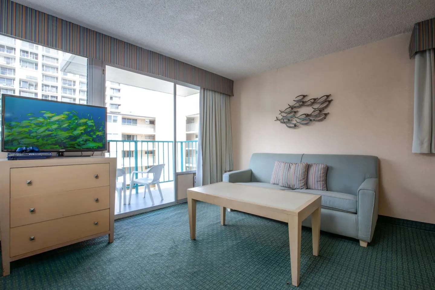 Deluxe Room sitting area with sofa and balcony at Aqua Aloha Surf Waikiki.
