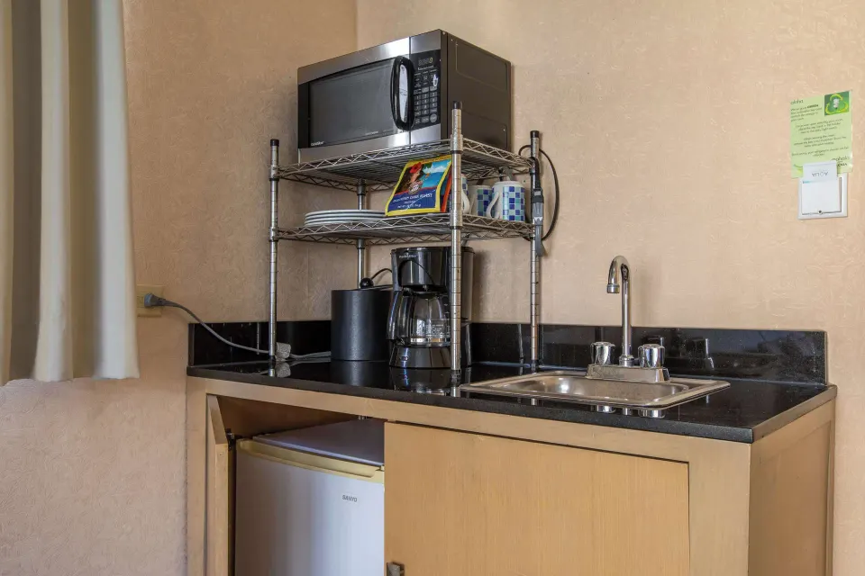 Junior Suite kitchenette with microwave, sink, coffee maker, and mini fridge at Aqua Aloha Surf Waikiki.