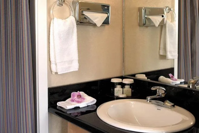 Moderate Room bathroom vanity with sink, mirror, towels, and toiletries at Aqua Aloha Surf Waikiki.