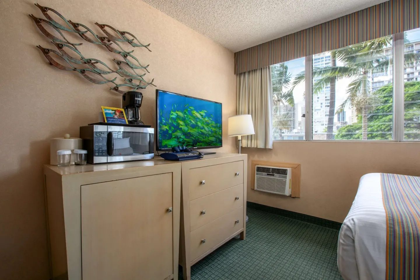 Moderate room with TV, microwave, dresser, fish wall art, and bed at Aqua Aloha Surf Waikiki.