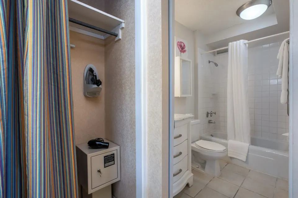 One-bedroom suite closet and bathroom with tub at Aqua Aloha Surf Waikiki.