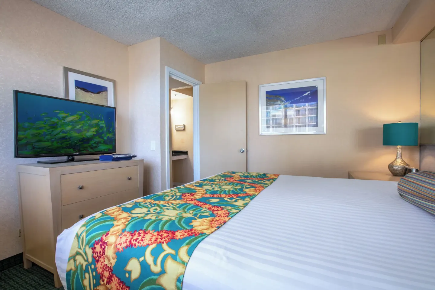 One-bedroom suite bedroom with bed and television at Aqua Aloha Surf Waikiki.