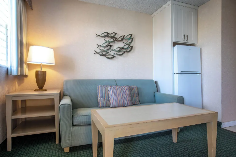 One-bedroom suite sitting area with sofa and refrigerator at Aqua Aloha Surf Waikiki.