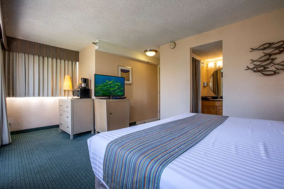 Superior Room with king bed, TV, dresser, and bath entry at Aqua Aloha Surf Waikiki.