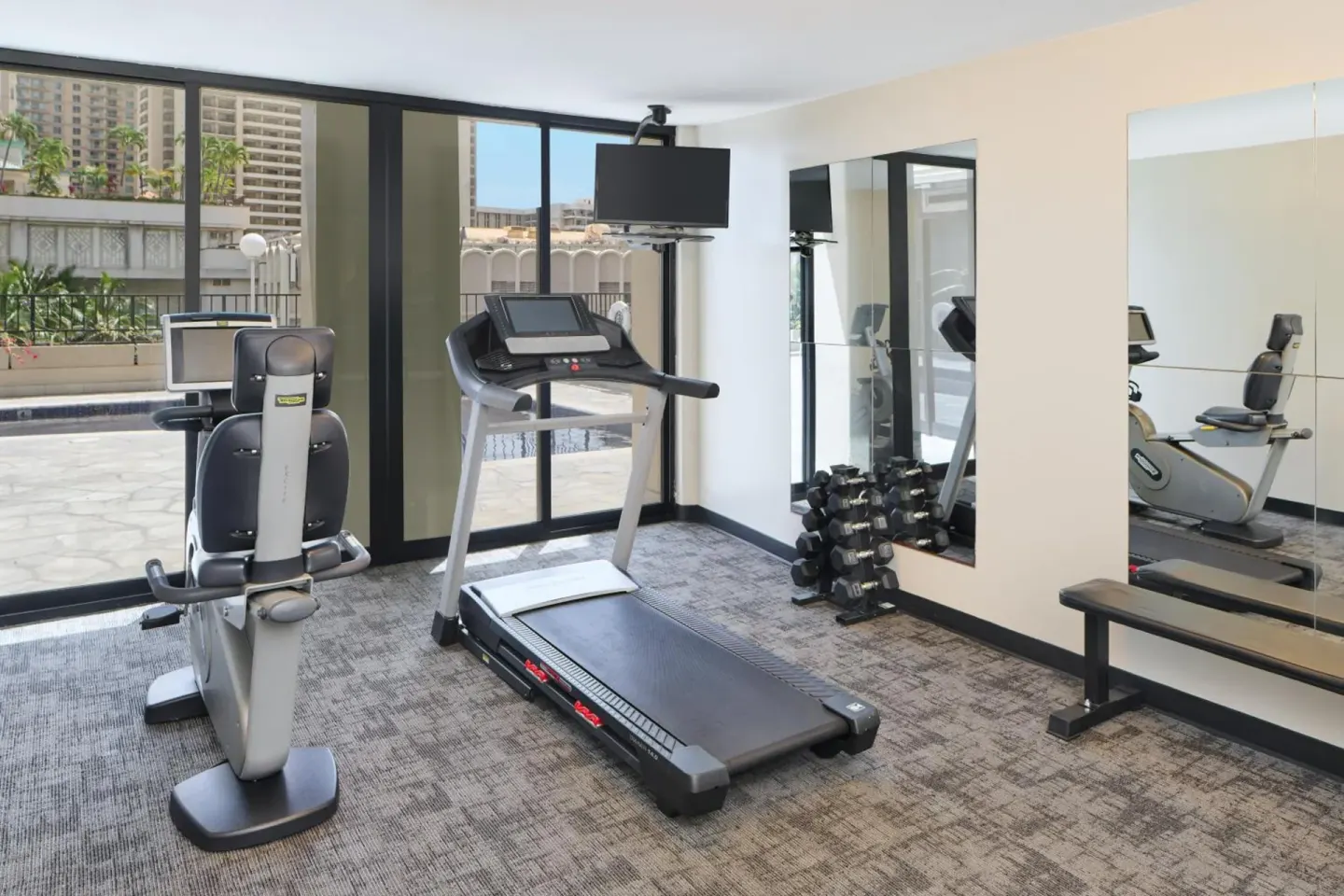 Fitness room with treadmill, recumbent bike and dumbbells at Aqua Palms Waikiki.