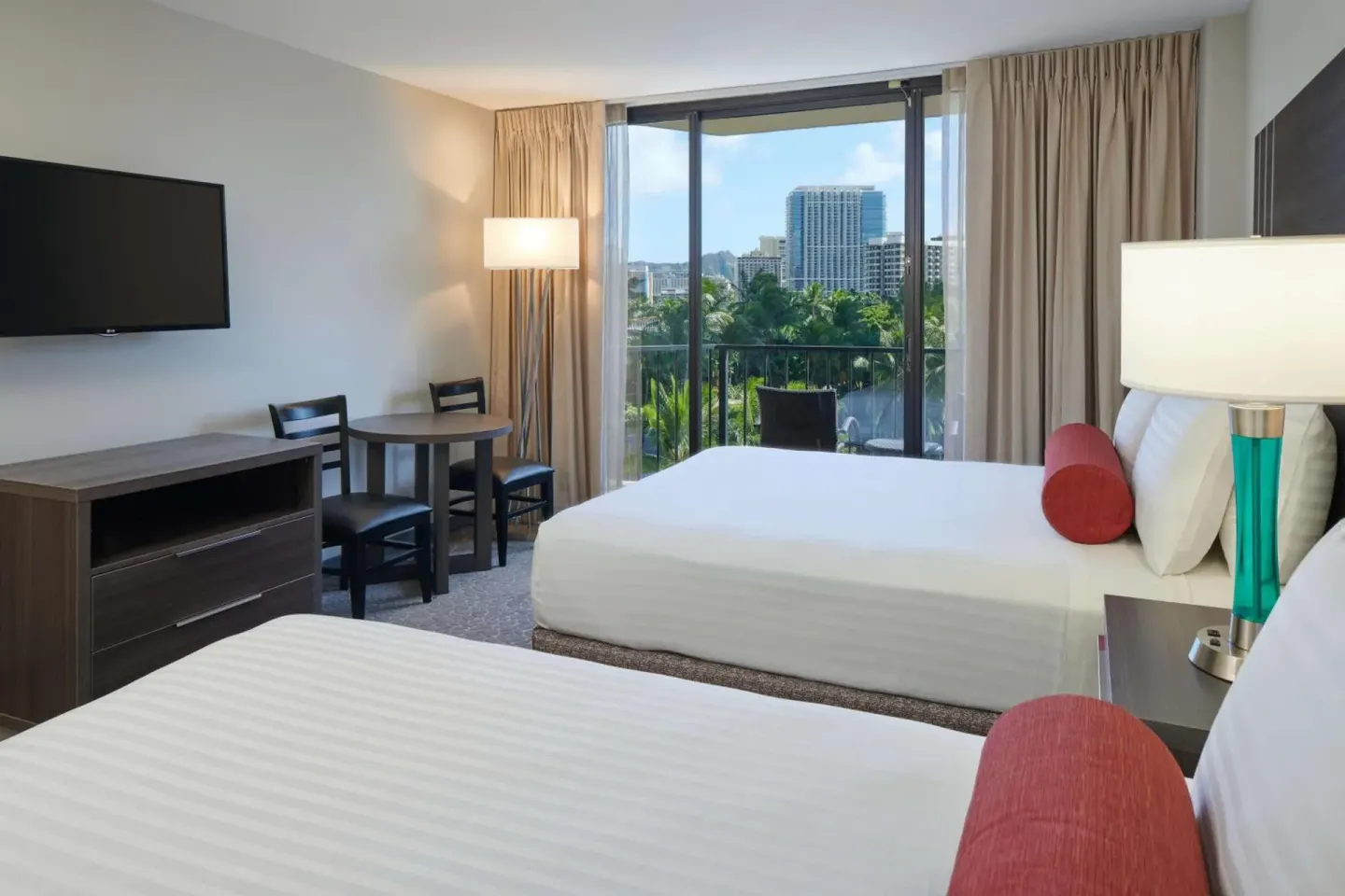 Guest room with two beds, desk, TV, and balcony view at Aqua Palms Waikiki.