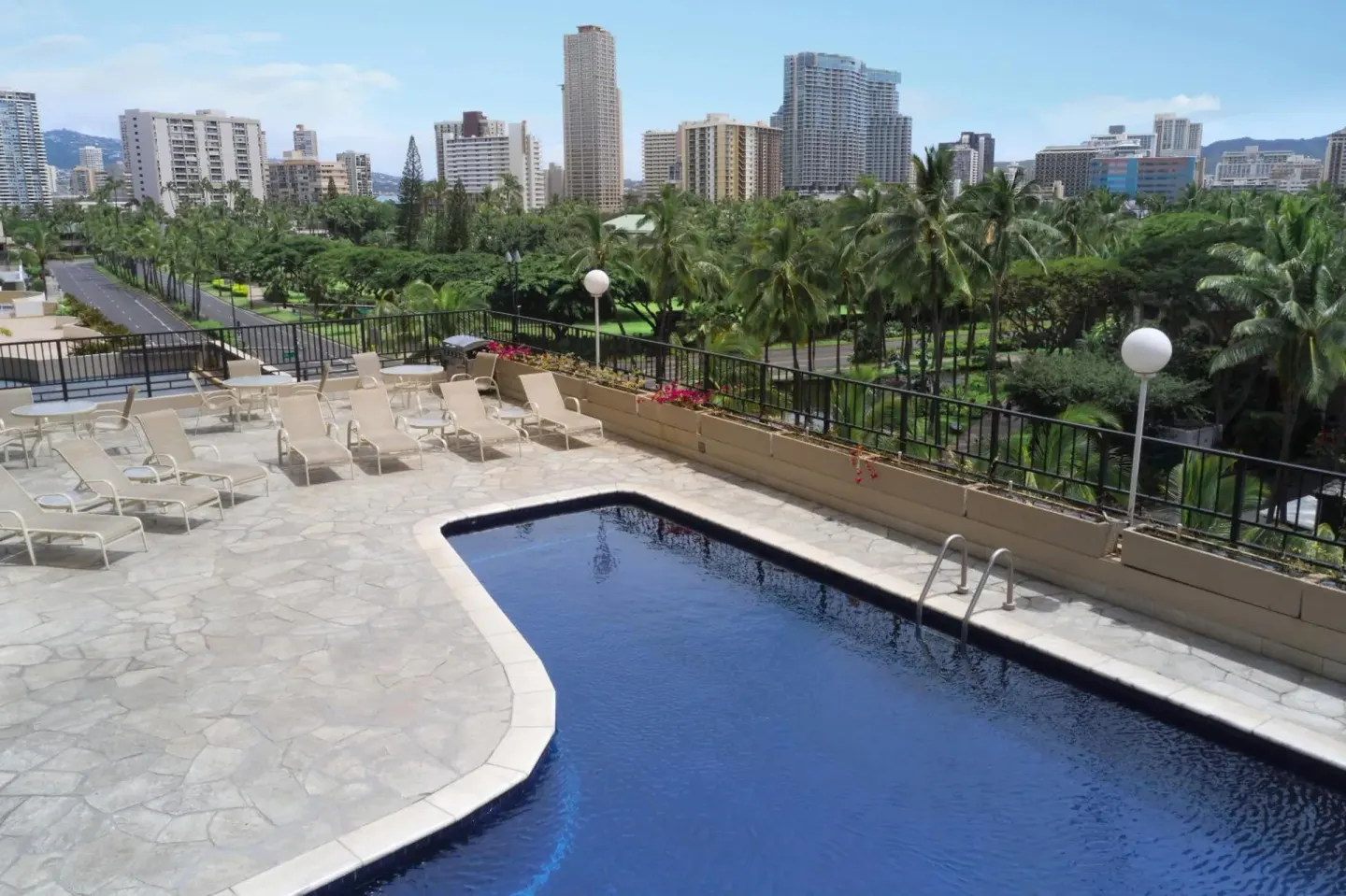 Outdoor pool deck with lounge chairs and Waikiki skyline views at Aqua Palms Waikiki.