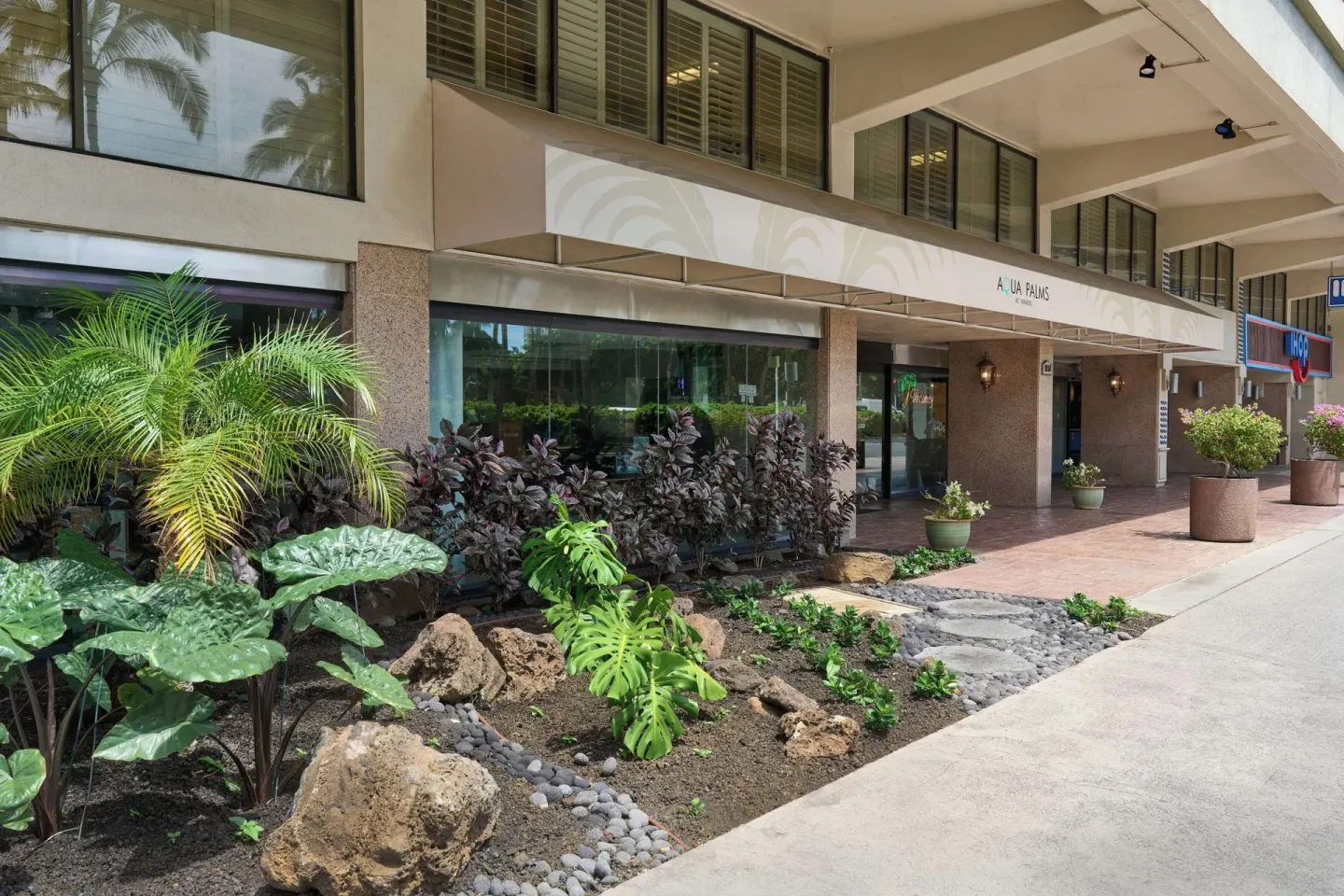Landscaped sidewalk garden and covered storefronts at Aqua Palms Waikiki.