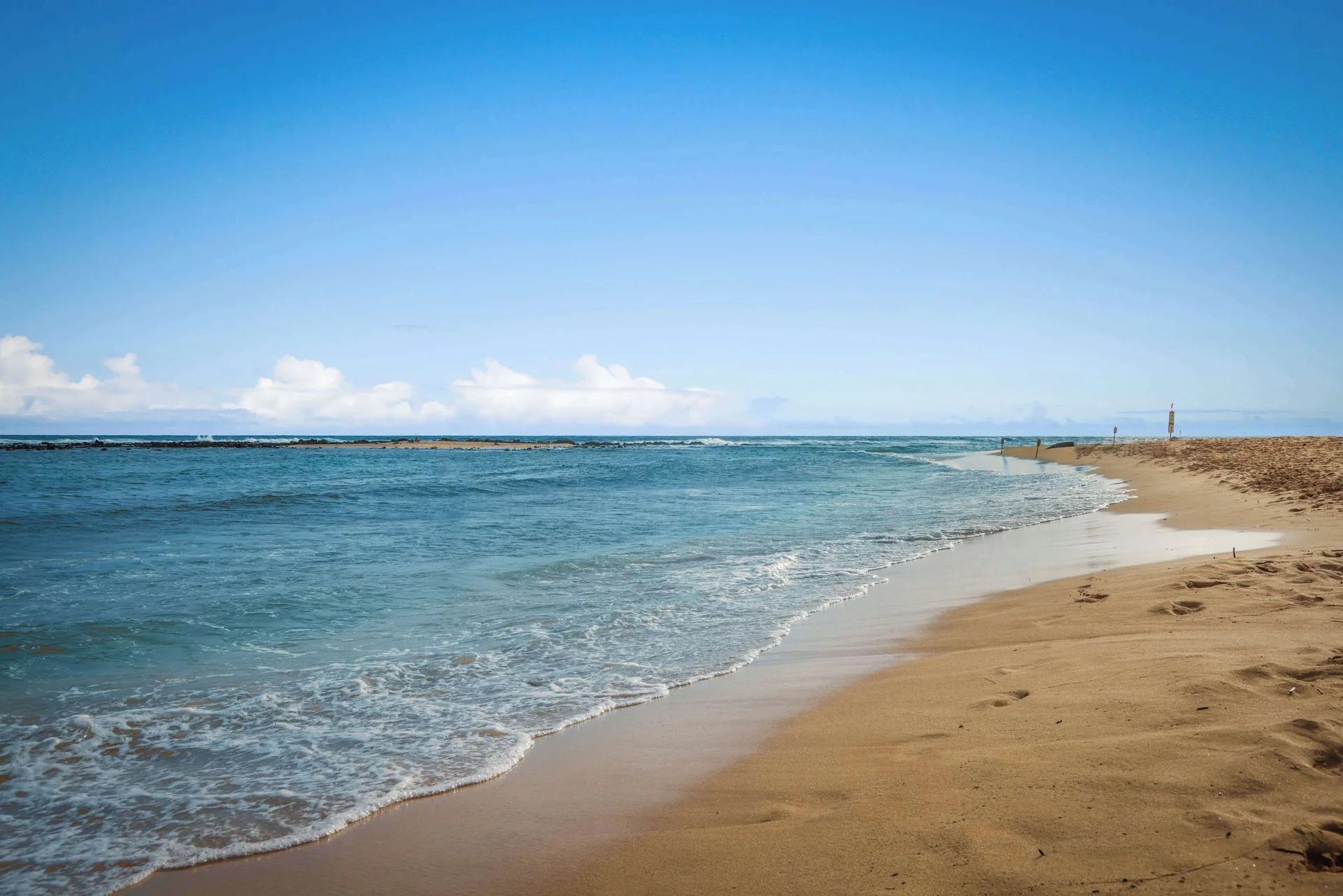 Curving sandy beach and blue ocean water near Aston at Poipu Kai.