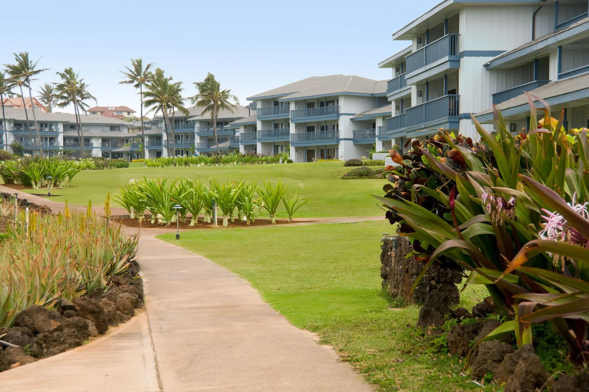 Curved walkway through lawns and tropical plantings at Aston at Poipu Kai.