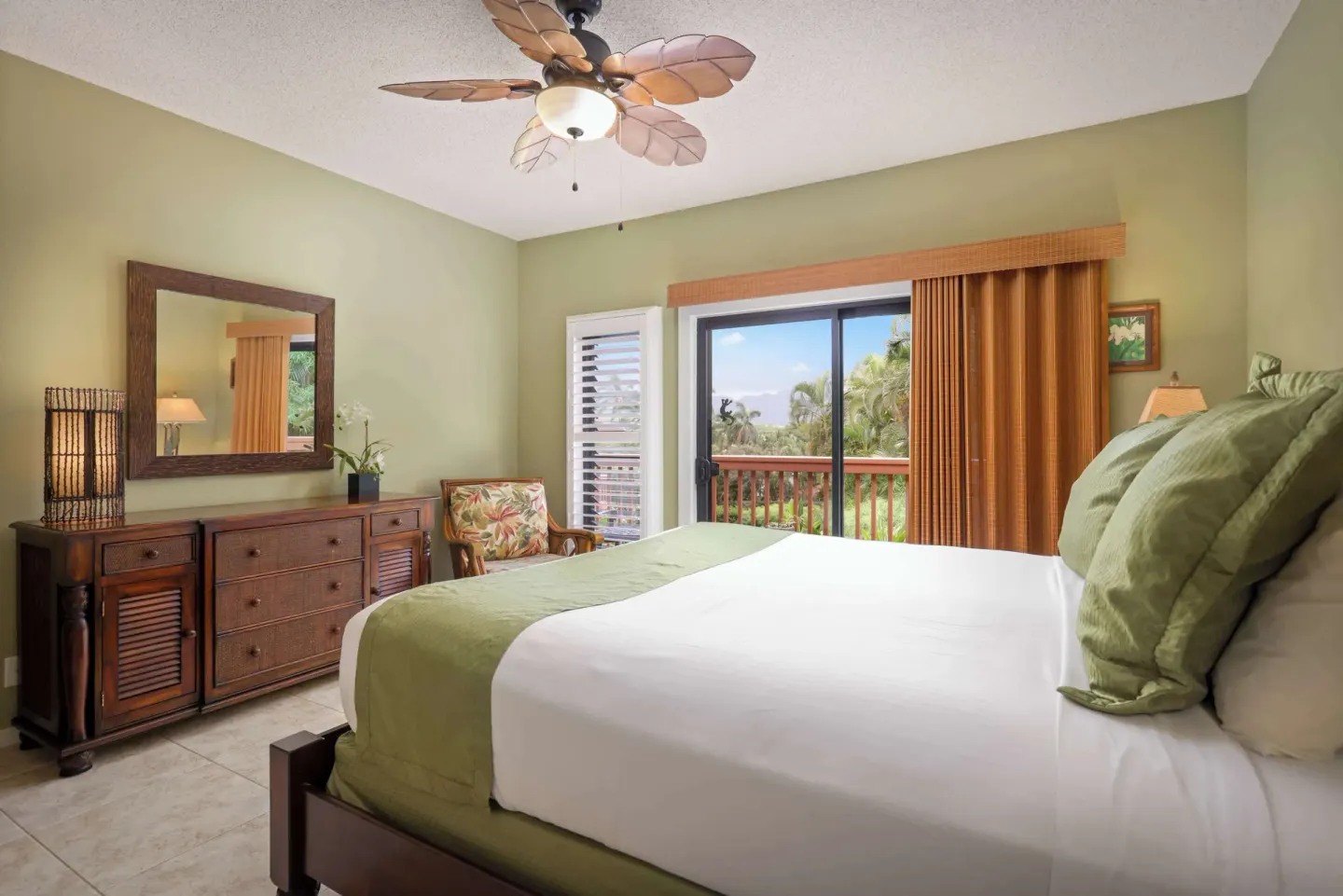 Guest bedroom with king bed, dresser, and balcony greenery at Aston at Poipu Kai.