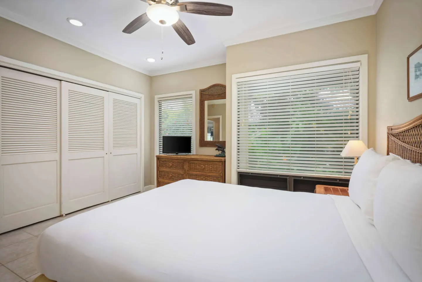 Guest bedroom with bed, closet doors, dresser and window blinds at Aston at Poipu Kai.