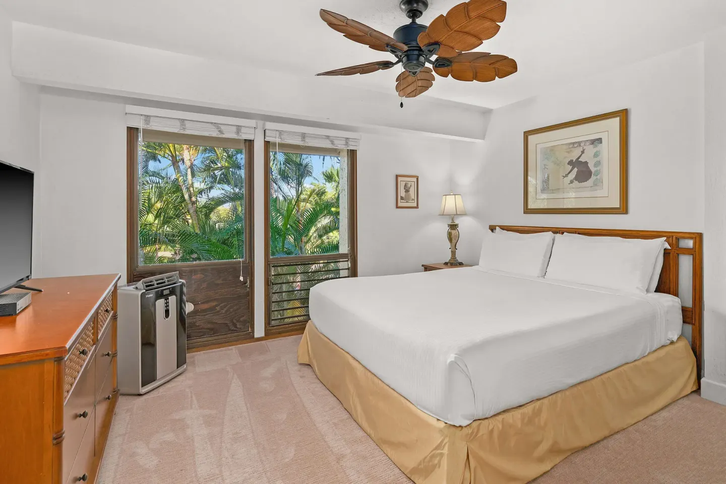 Guest bedroom with king bed, leafy ceiling fan and garden-facing windows at Aston at Poipu Kai.