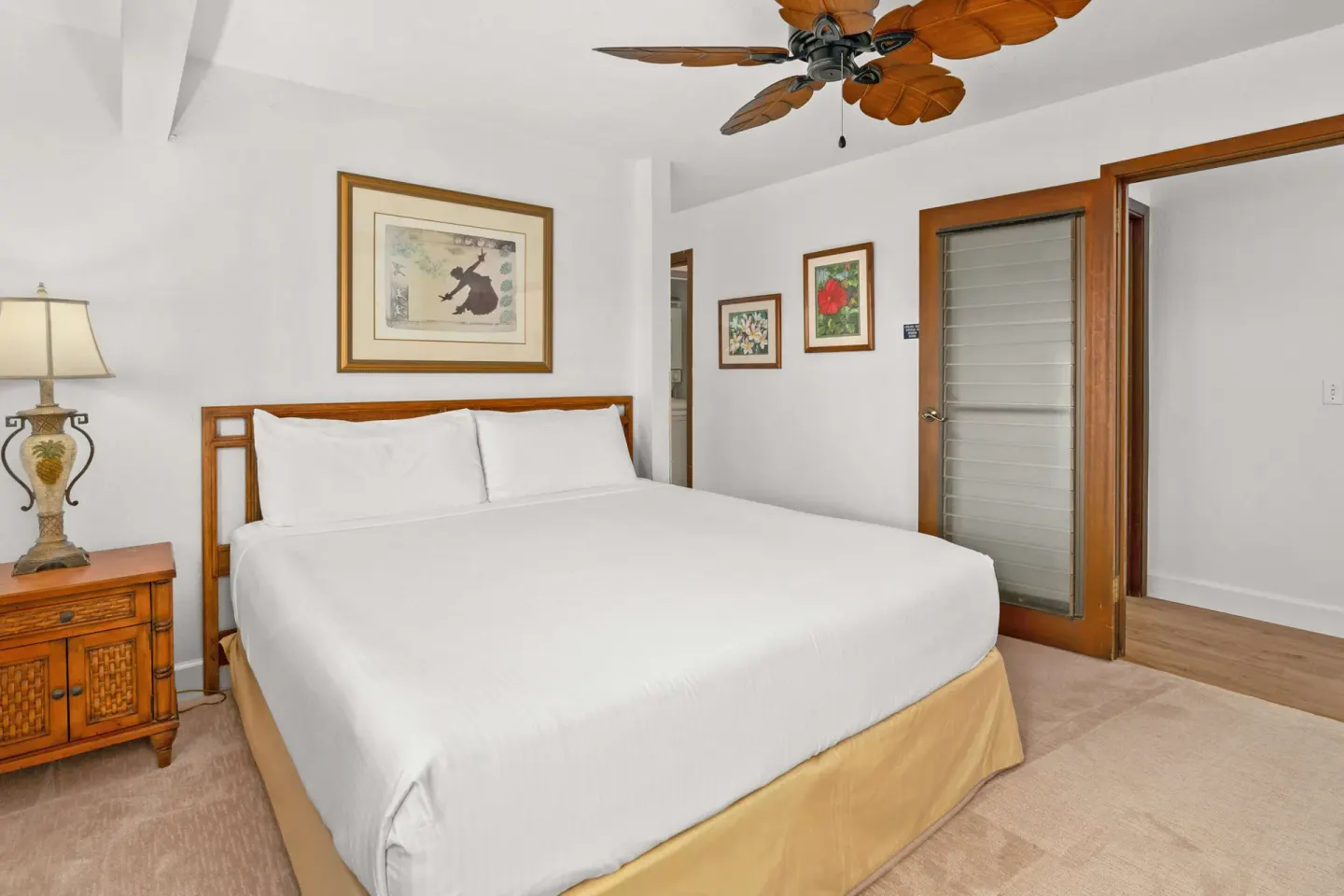 Guest bedroom with king bed, wood nightstand and glass door at Aston at Poipu Kai.
