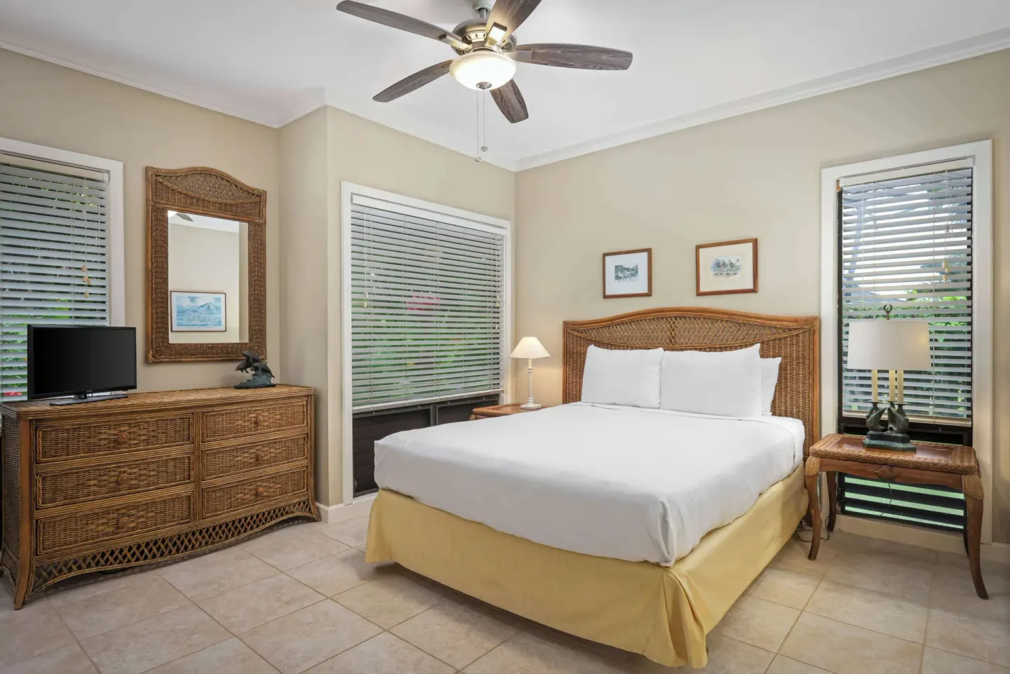 Guest bedroom with king bed, wicker furniture and large windows at Aston at Poipu Kai.