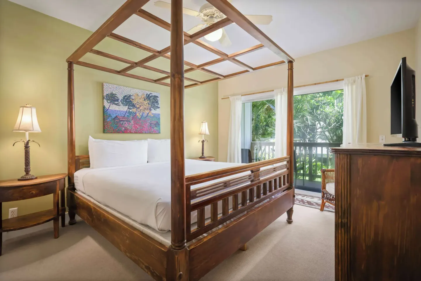 Four-poster king bedroom with balcony doors and wood dresser at Aston at Poipu Kai.