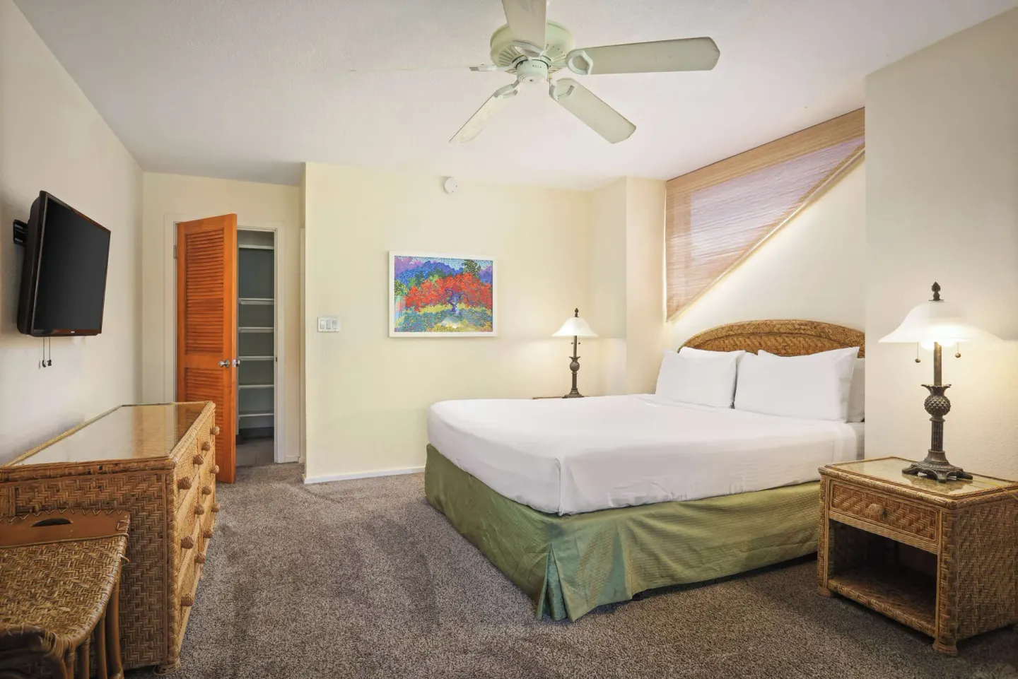 King bedroom with wicker dresser, open closet, and wall-mounted TV at Aston at Poipu Kai.