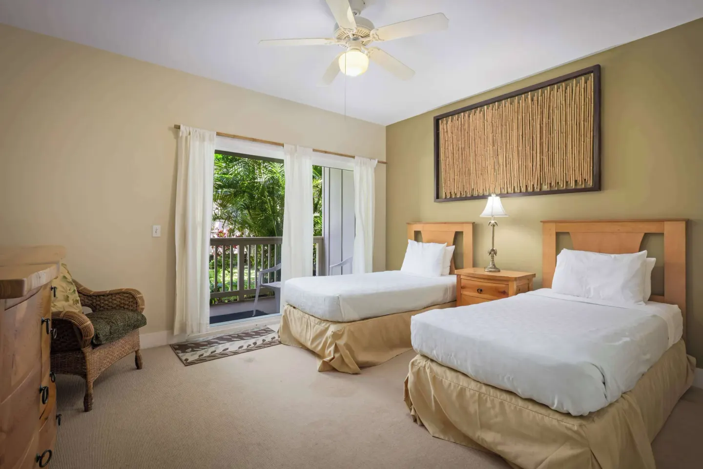 Two twin beds with balcony doors and bamboo wall art at Aston at Poipu Kai.