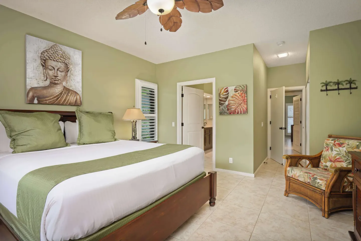 King bedroom with wall art, armchair, and open bathroom doorway at Aston at Poipu Kai.