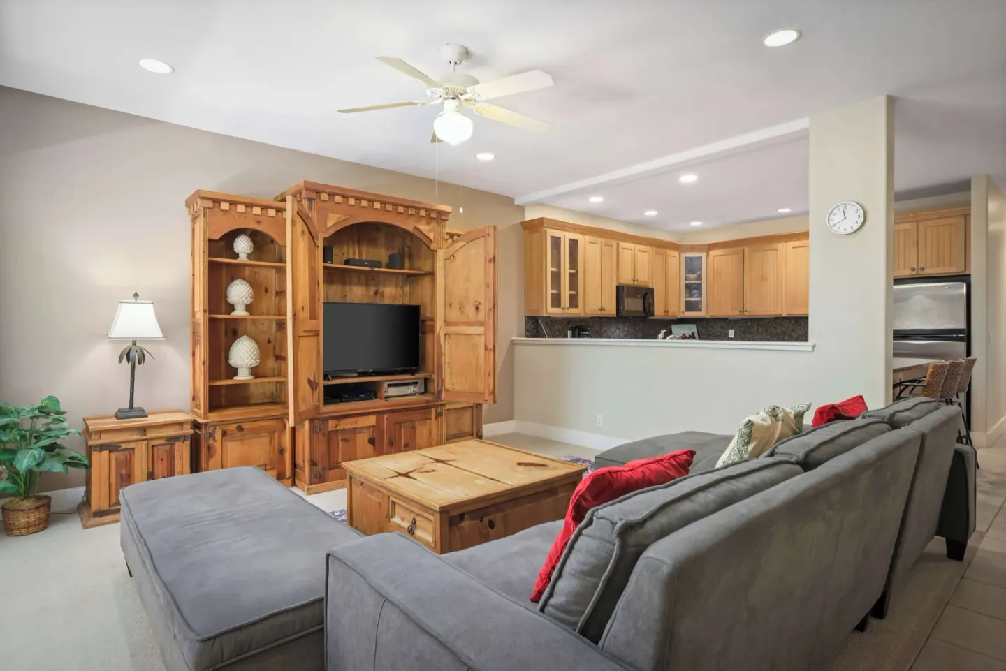 Living room with sectional sofa, wood media cabinet, and open kitchen at Aston at Poipu Kai.