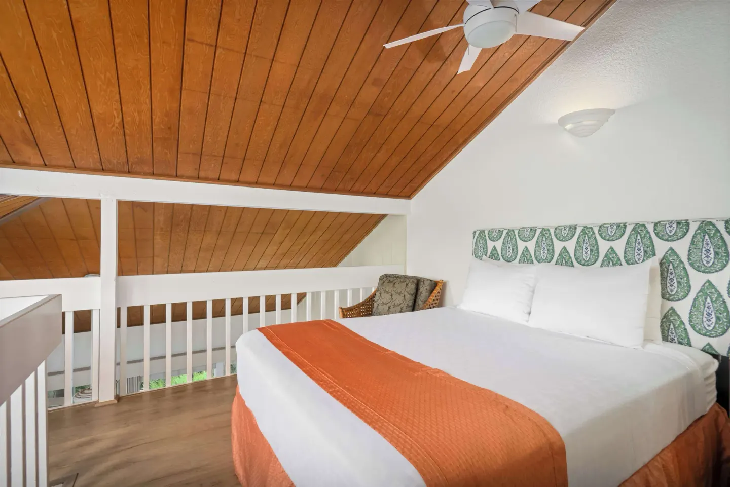 Loft bedroom with queen bed, wood ceiling, railing, and ceiling fan at Aston at Poipu Kai.