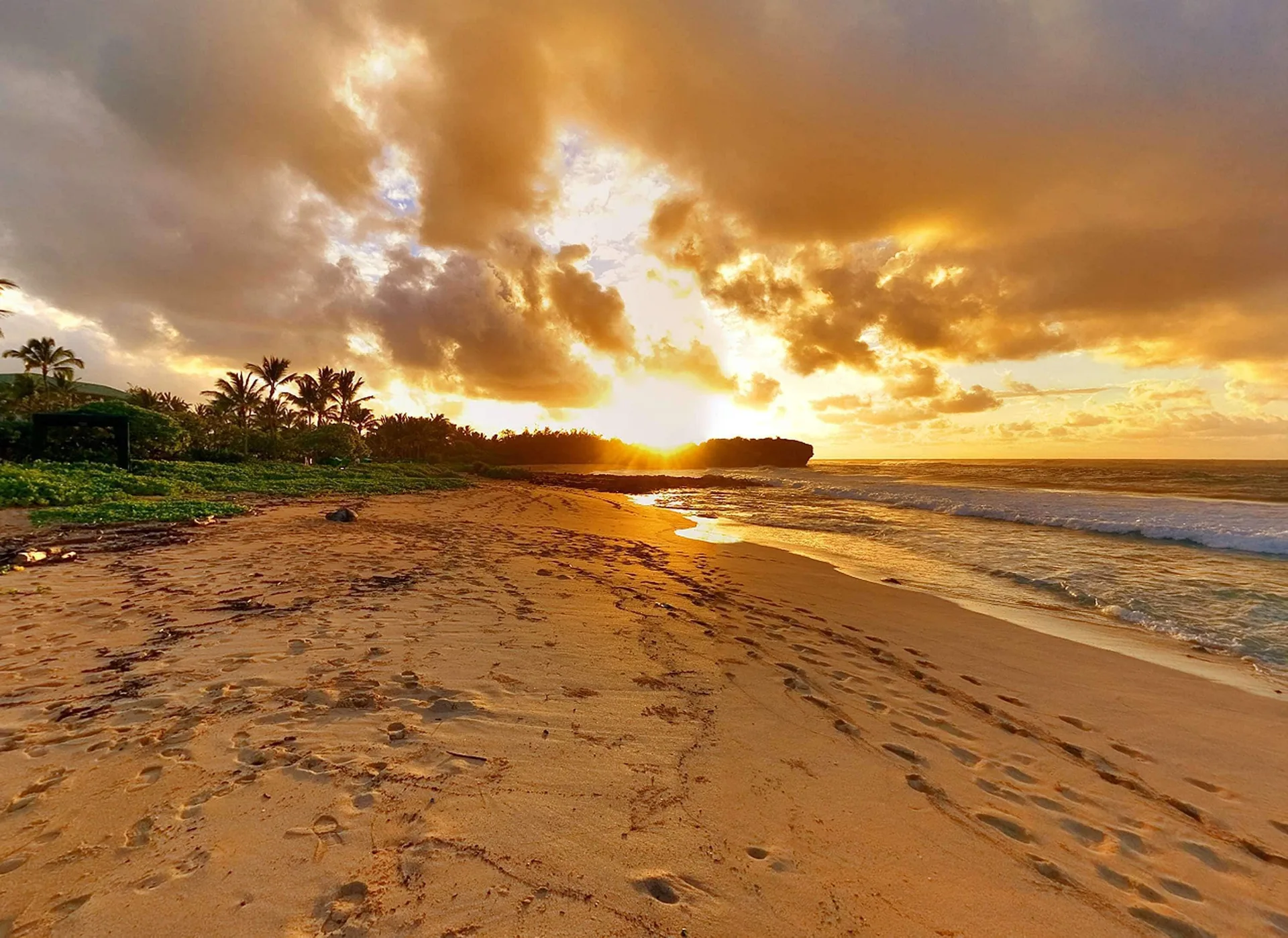 Golden sunset over a sandy beach near Aston at Poipu Kai with surf and clouds.