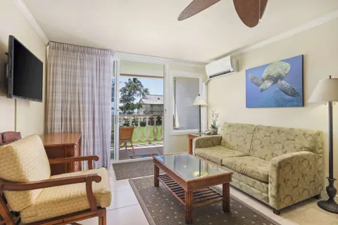 Guest room sitting area with sofa and balcony at Aston Islander on the Beach.