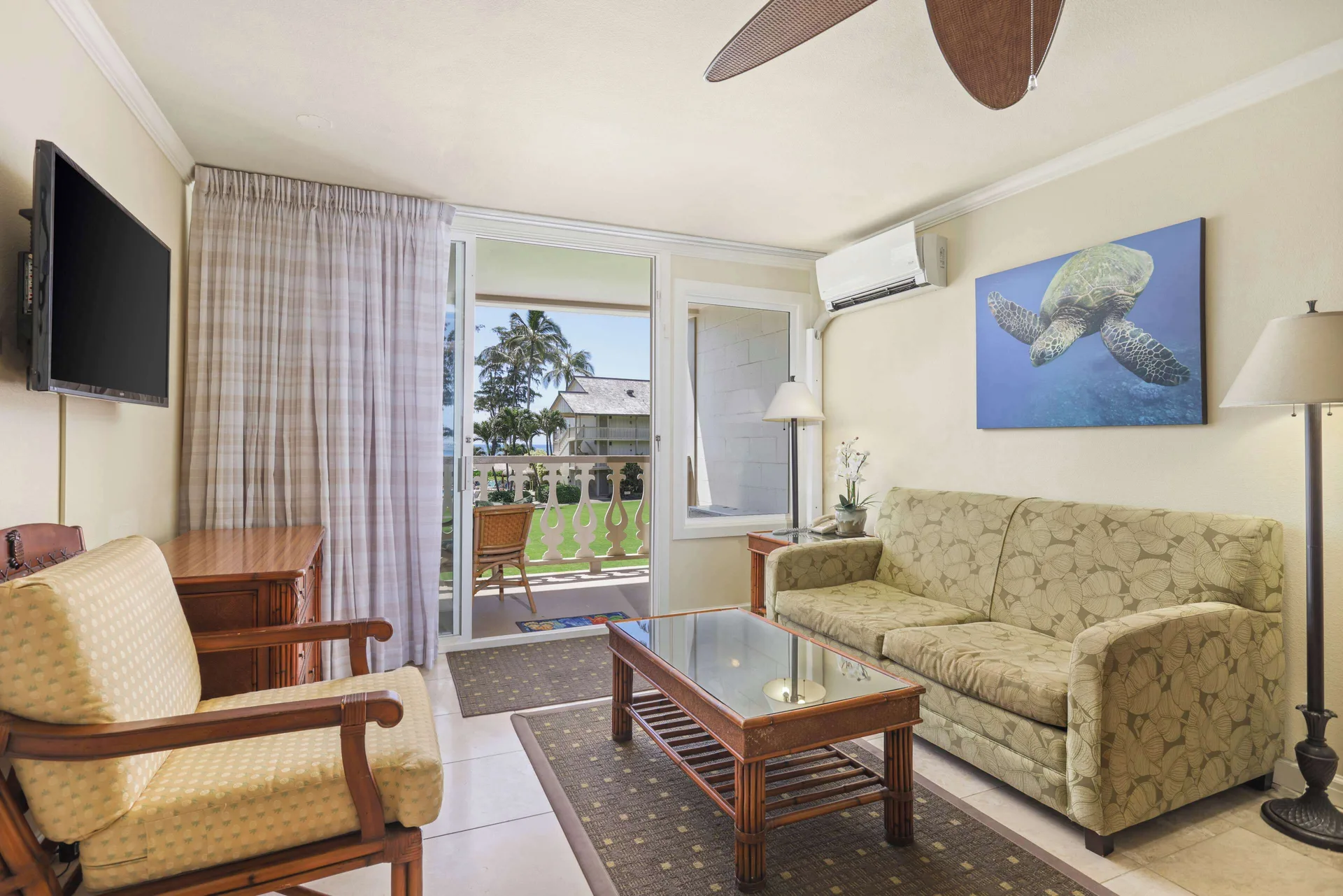 Guest room sitting area with sofa and balcony at Aston Islander on the Beach.