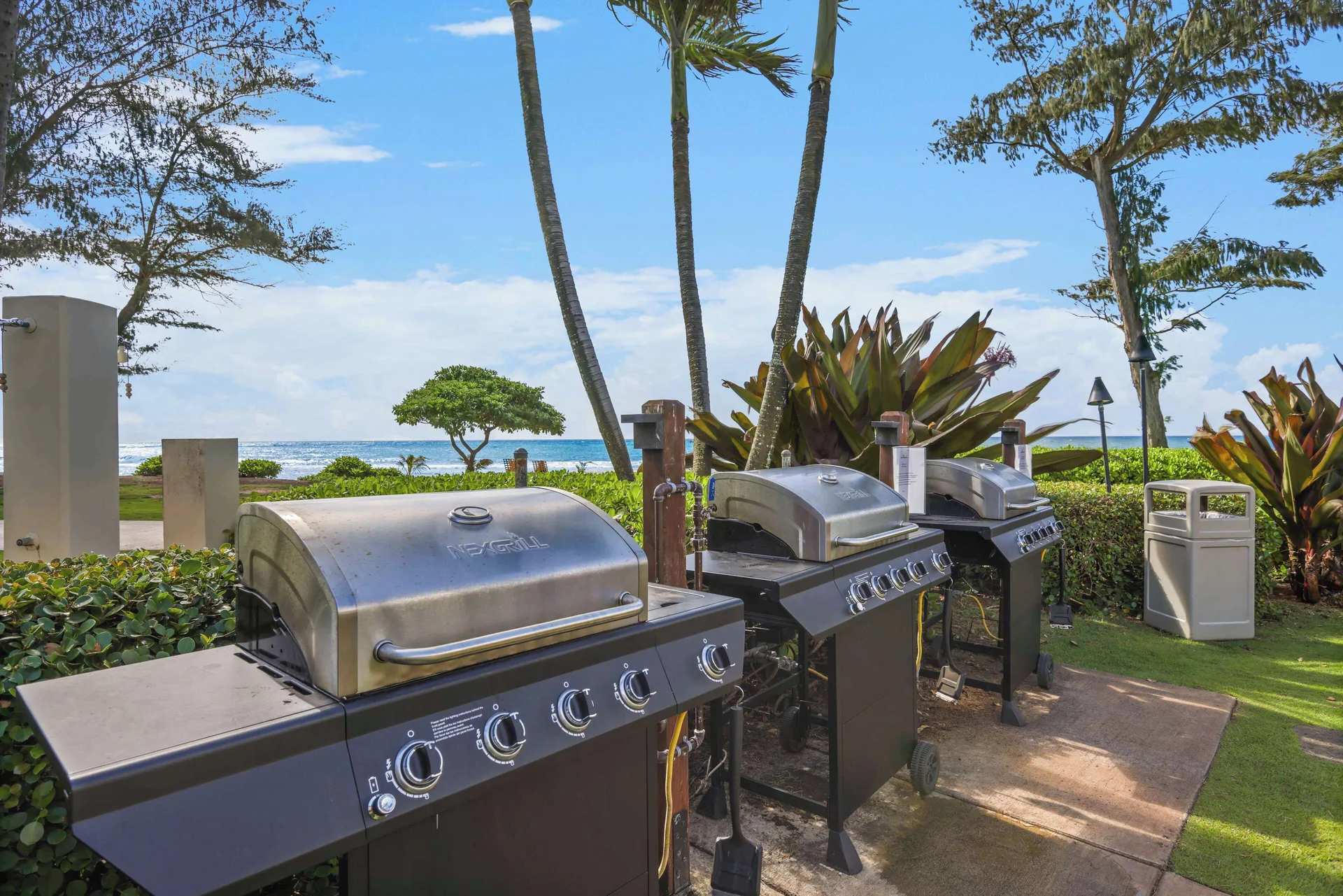 Barbecue grills with ocean and palms behind them at Aston Islander on the Beach.
