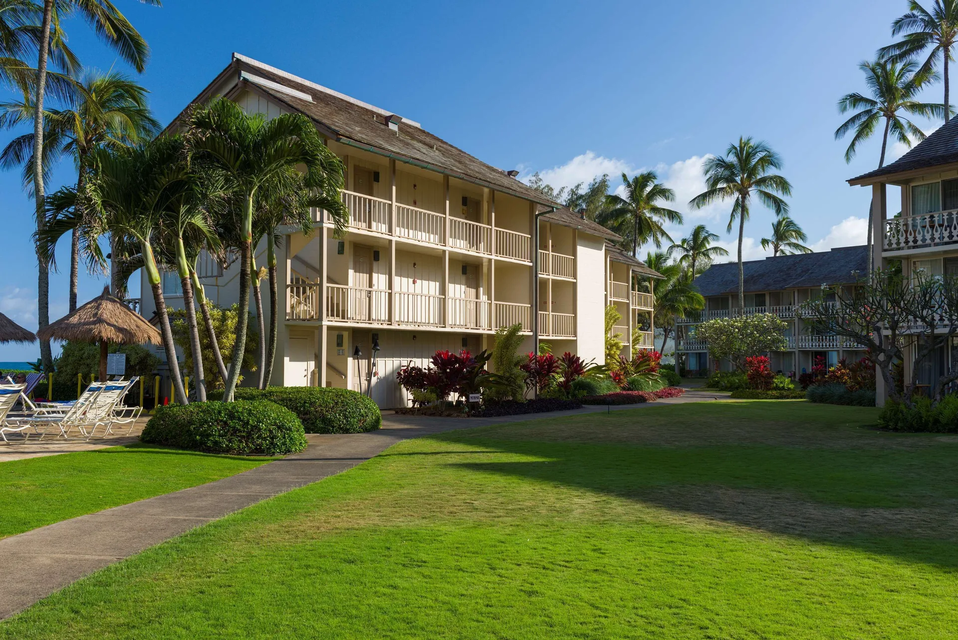 Resort lawn, guest room balconies, and poolside seating at Aston Islander on the Beach.