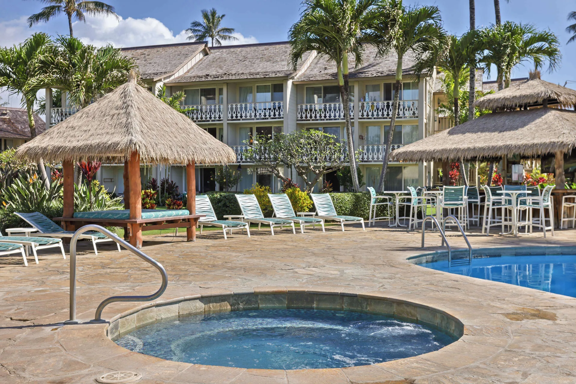 Spa and pool deck with lounge chairs and resort building at Aston Islander on the Beach.