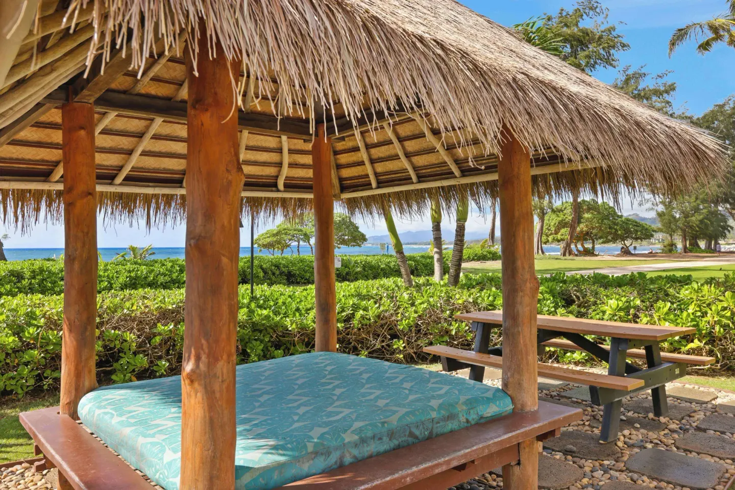 Thatched daybed and picnic table by the ocean at Aston Islander on the Beach.