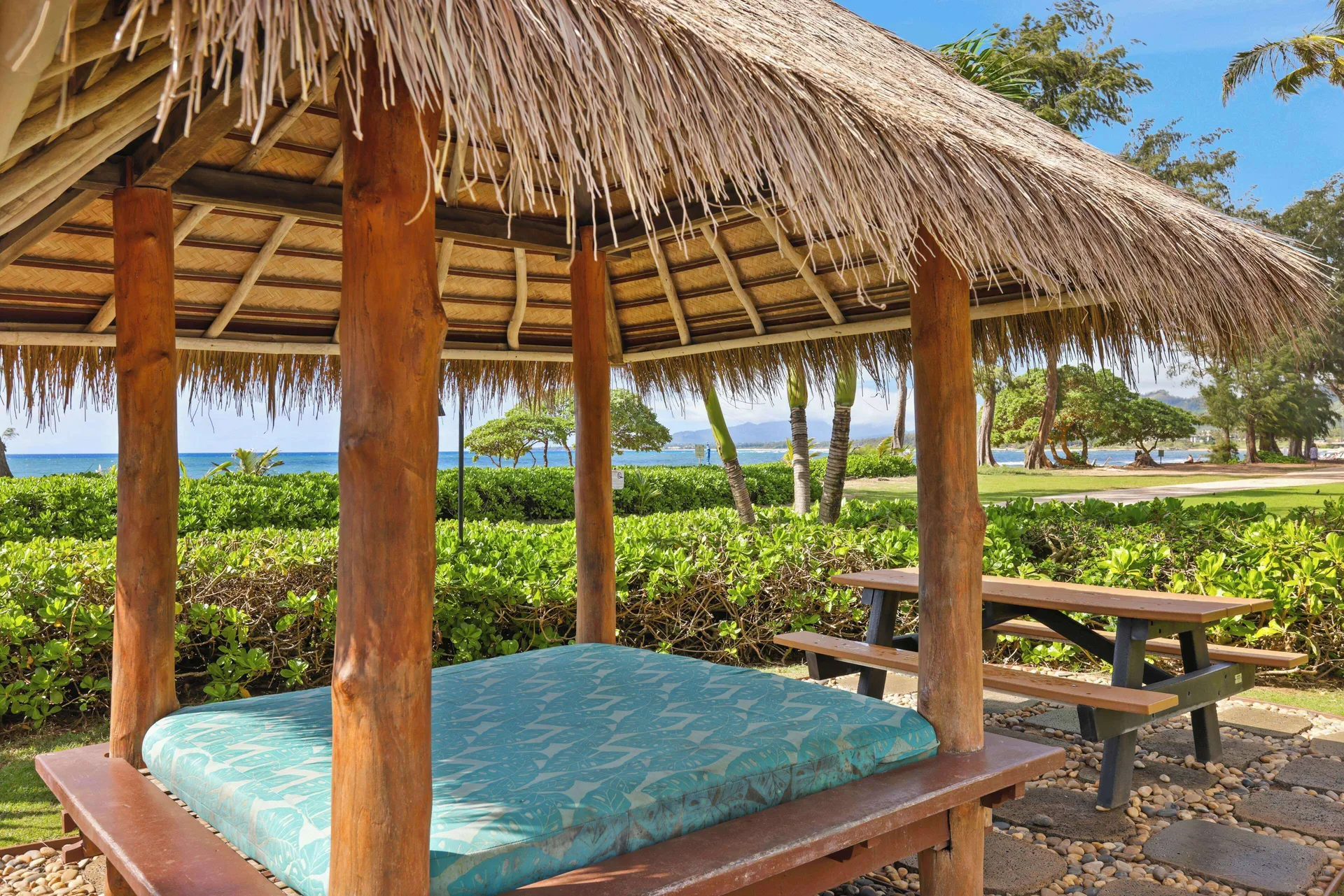 Thatched daybed and picnic table by the ocean at Aston Islander on the Beach.