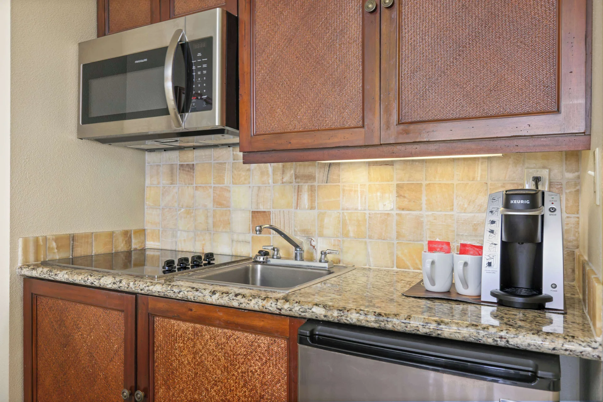 Panoramic Suite kitchenette with sink, cooktop, microwave and coffee maker at Aston Islander on the Beach.