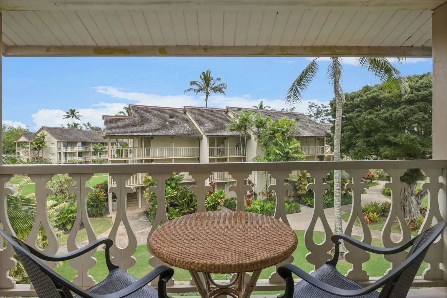 Garden View room balcony with table, chairs, and landscaped grounds at Aston Islander on the Beach.