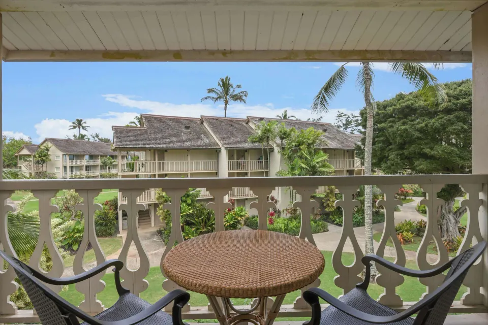 Garden View room balcony with table, chairs, and landscaped grounds at Aston Islander on the Beach.
