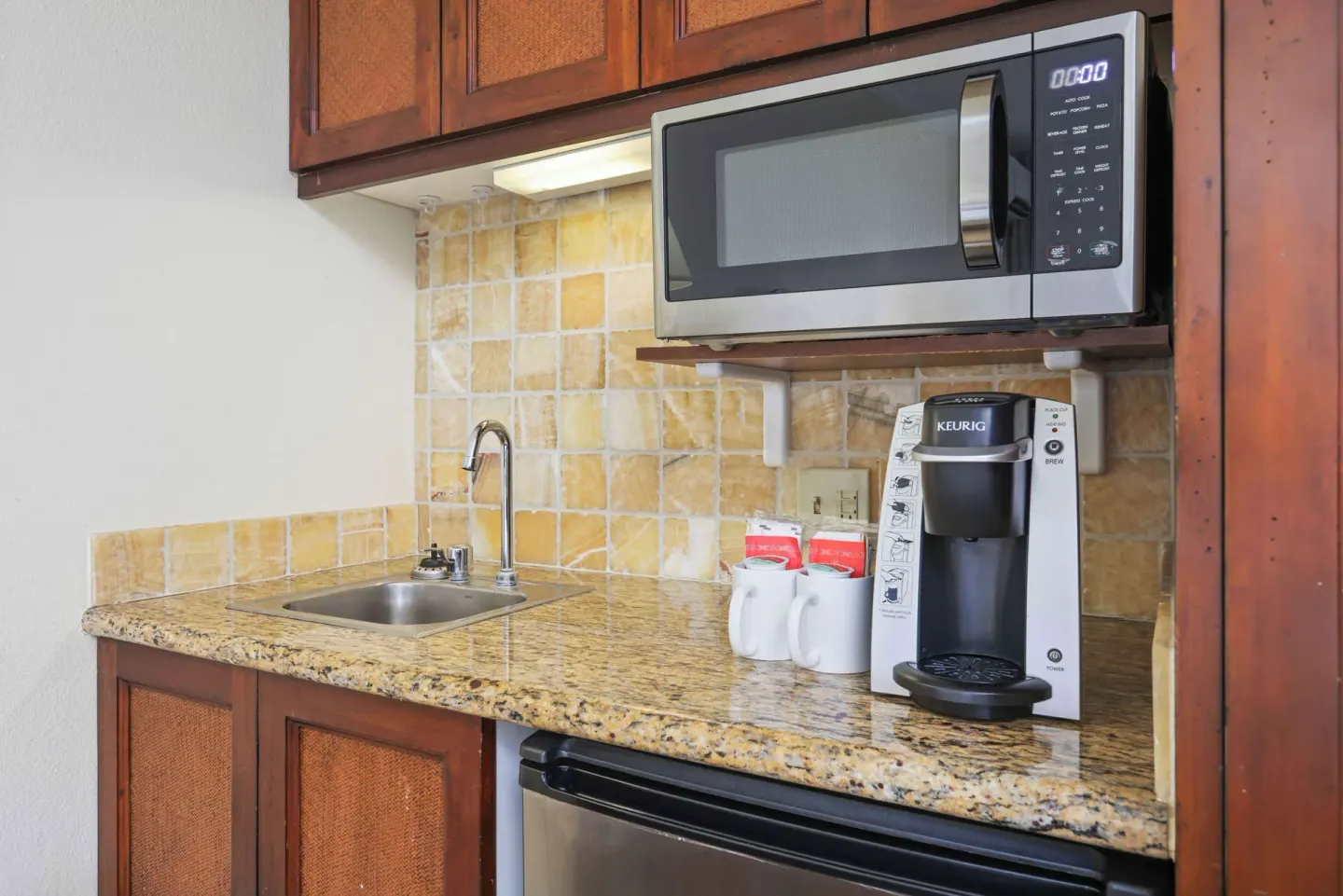 Garden View room kitchenette with sink, microwave, coffeemaker, and mini fridge at Aston Islander on the Beach.