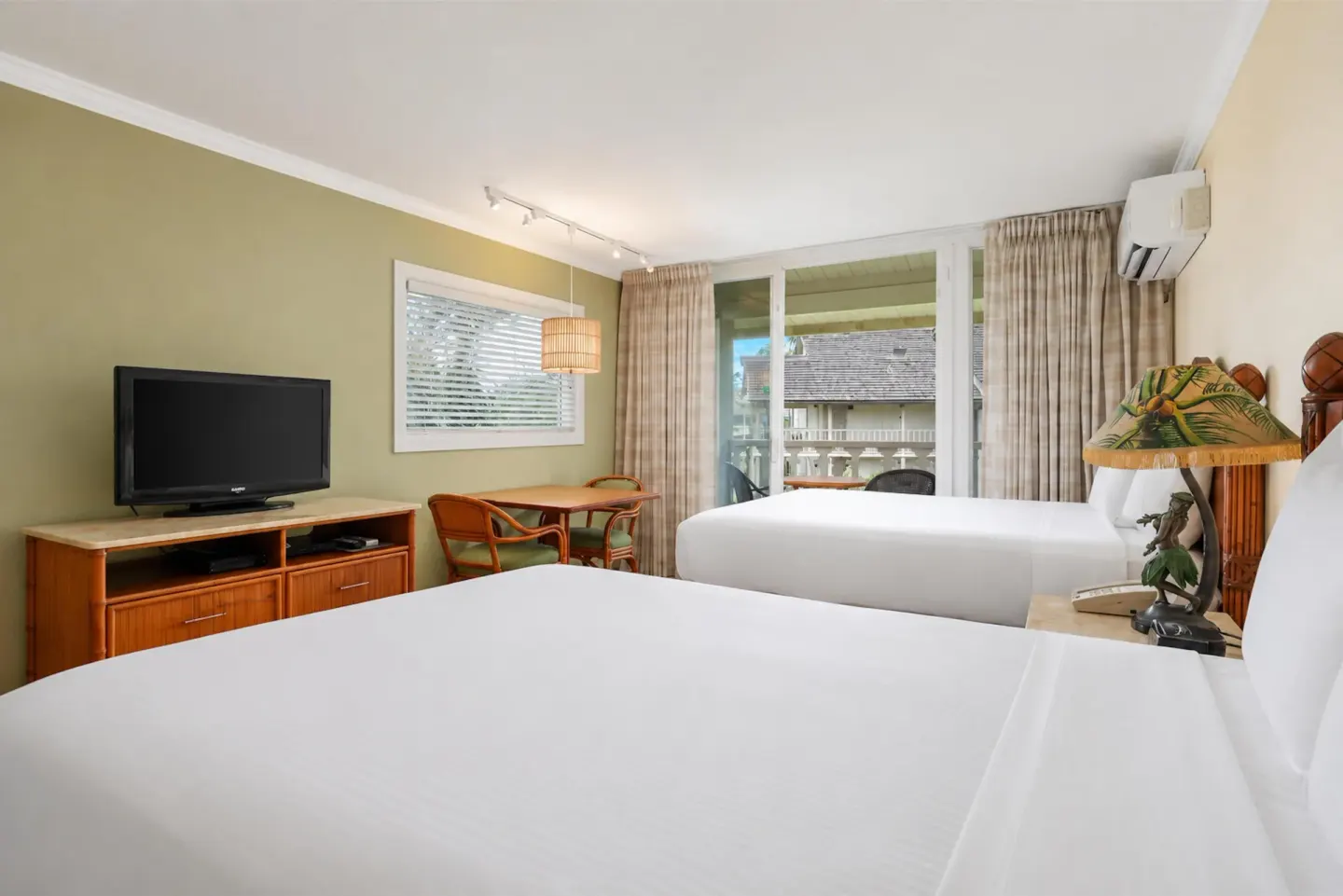 Garden View room with two beds, TV, dining table, and balcony at Aston Islander on the Beach.