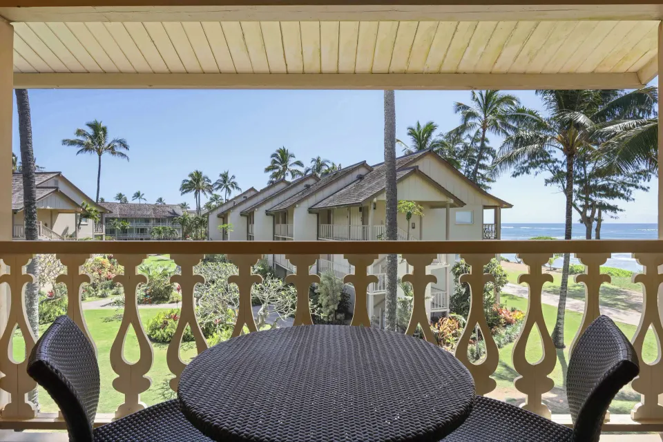 Ocean View room balcony table overlooking gardens, palms, buildings, and ocean at Aston Islander on the Beach.
