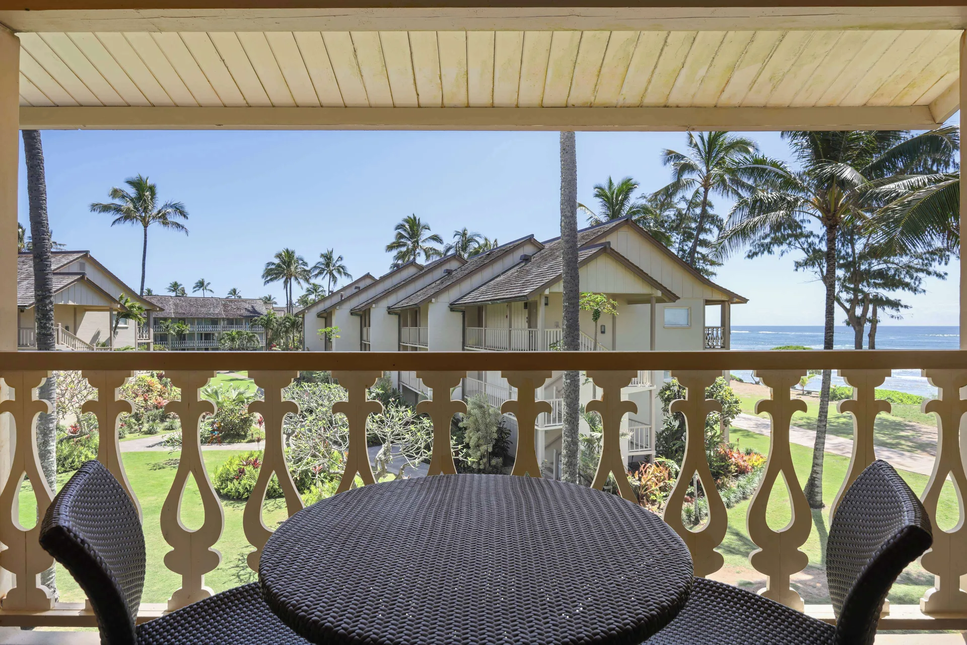 Ocean View room balcony table overlooking gardens, palms, buildings, and ocean at Aston Islander on the Beach.