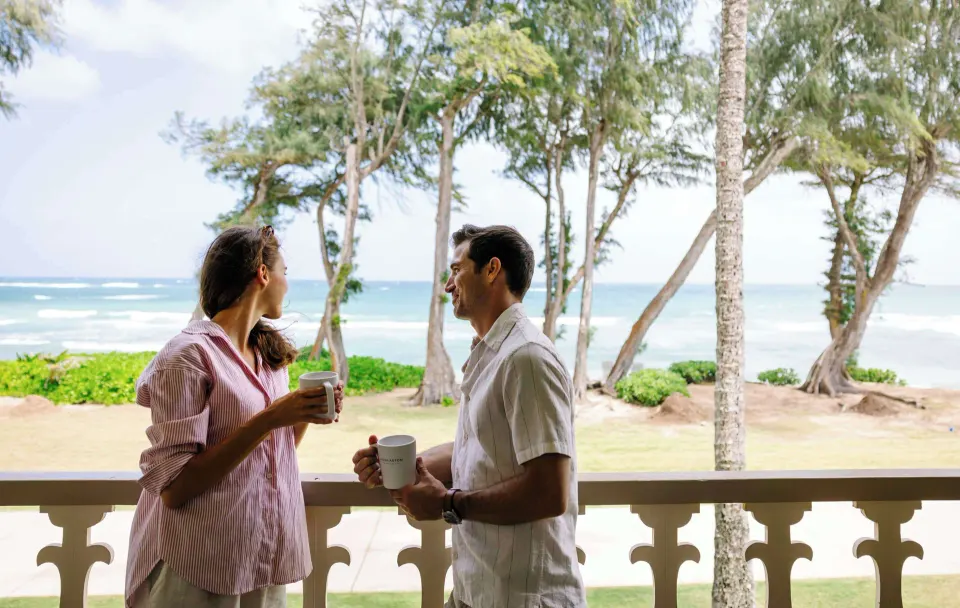 Guests holding mugs on an oceanfront balcony at Aston Islander on the Beach.