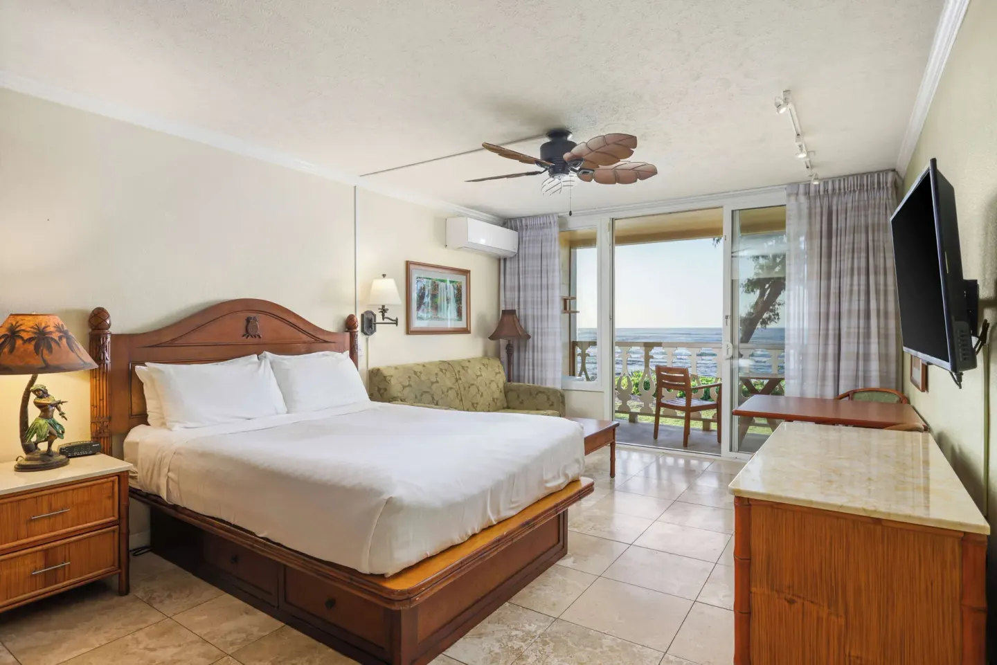 Oceanfront room with king bed, sofa, TV, and balcony view at Aston Islander on the Beach.